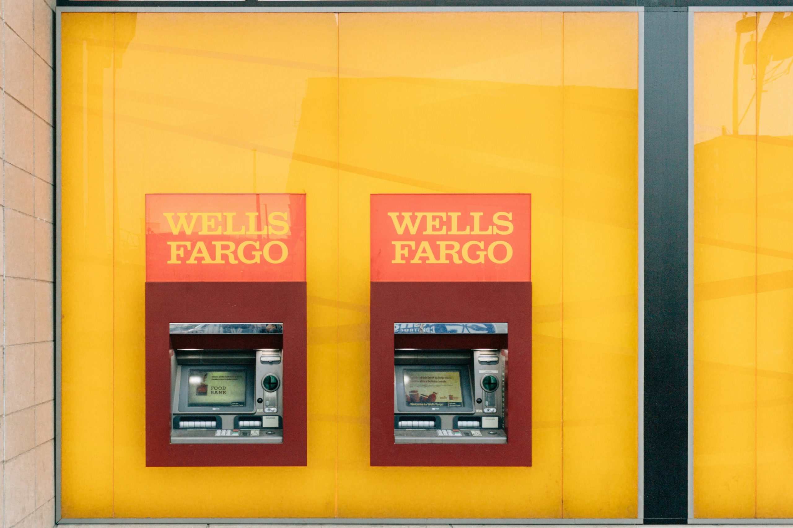 Two wells fargo atm machines on a yellow wall. 